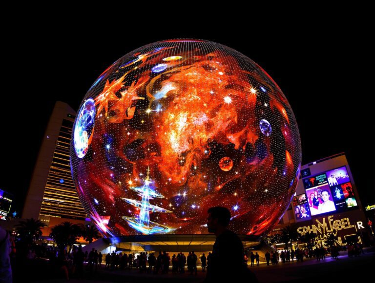 Sphere Las Vegas at night displaying cosmic imagery on its massive LED exterior, home to Postcard From Earth experience